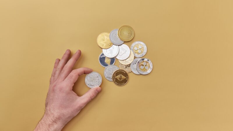 Hand Reaching for Crypto Coins on Table Representing Crypto Wealth Crypto Holders Vitalik Buterin Crypto Security and Blockchain