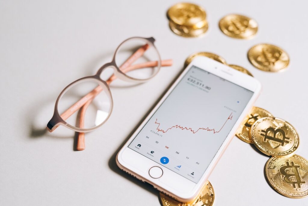 Crypto market chart displayed on a smartphone with Bitcoin coins, representing XRP price, Doge price, XRP price forecast, Doge price forecast, and XRP Doge market trends.
